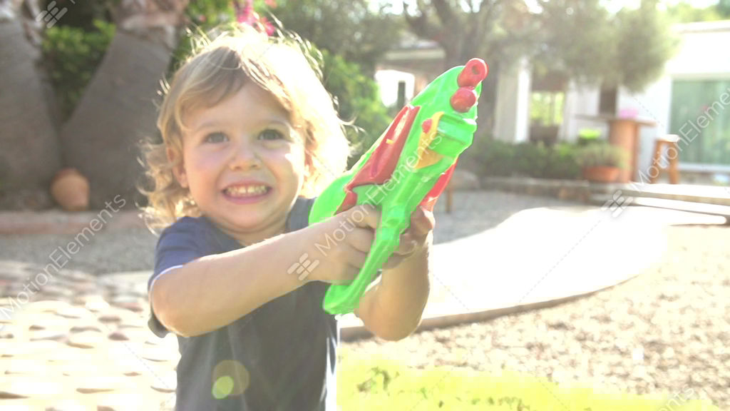 Slow Motion Shot Of Boy Squirting Water Pistol In Garden Stock Video Footage Slow Motion Shot Of Boy Squirting Water Pistol In Garden Stock Video Footage