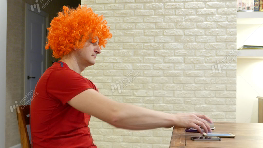 Funny Guy In Orange Afro Wig Sit By Table, Cant Choose Mobile Device