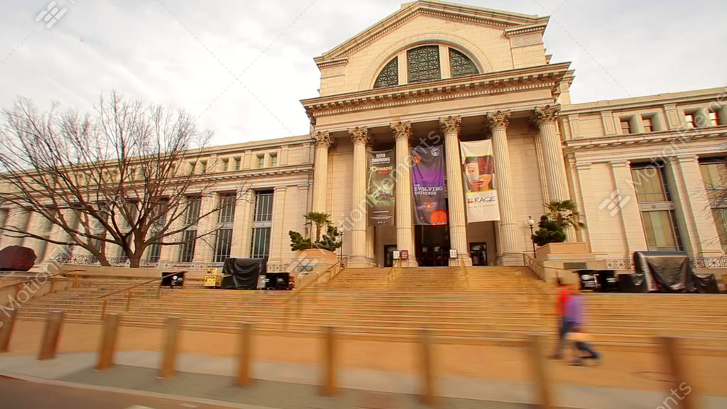 tracking shot of a building with ionic pillars and many windows in