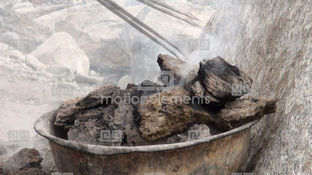 Poking Burning Manure Near A Traditional Yurt Stock video footage 1675520